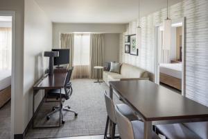 カンザスシティにあるResidence Inn by Marriott Kansas City at The Legendsのデスクとベッドルームが備わるホテルルームです。
