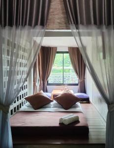 Bett in einem Zimmer mit Fenster in der Unterkunft บ้านพักบุหงา199 อ สรรพยา in Sanphaya