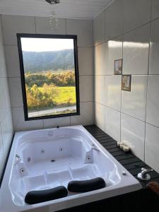 a large bath tub in a bathroom with a window at Pousada Recanto entre Rios CHALE SOL NASCENTE in Urubici