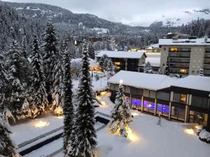 a resort with snow covered trees and a building at Laax with indoor and outside pool, sauna, 200 Meter to Ski lift , Fitnessroom, Tennis Place, Joyroom, Parkstadion Reserve in Laax