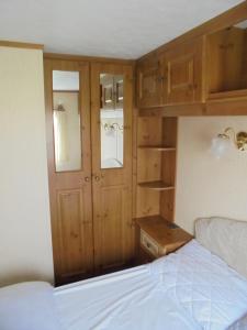 a small bedroom with a bed and wooden cabinets at Sealands : Arronbrook:- 6 Berth, Access to the beach, Close to site entrance in Ingoldmells