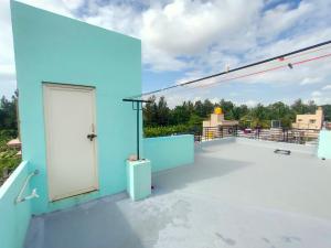 una puerta blanca en el techo de un edificio azul en Akshay Sweet Home Stay, en Mysore