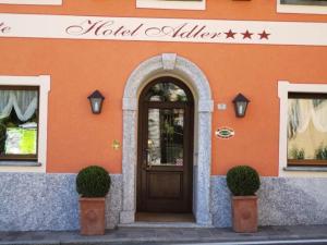 an orange building with a wooden door in front at Hotel Adler in Menaggio