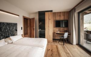 Dormitorio con cama, escritorio y TV en Wagnerhof Apartments en Pertisau