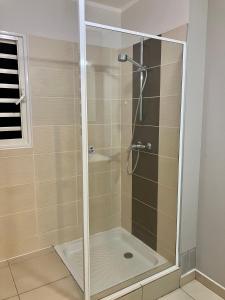 a shower with a glass door in a bathroom at chez Gérald in Noumea
