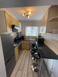 a kitchen with wooden cabinets and a black counter top at Luxury 2 bedroom maisonette with private garden, fibre WIFI, Sky channels in Camberley