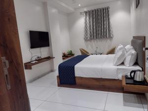 um quarto de hotel com uma cama e uma televisão em The Sky Land Hotel & Restaurant em Tuljapur