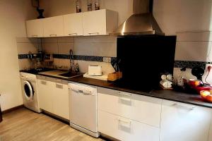 a kitchen with white cabinets and a washer and dryer at Magnifique T2 in Ajaccio