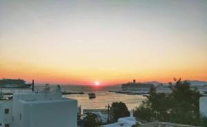 a sunset over a body of water with a harbor at Merriam mykonos town in Mikonos