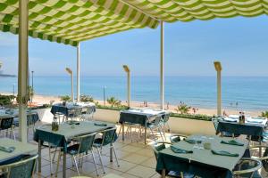 a restaurant with tables and chairs and the beach at Hotel Llorca in Platja de l’Almadrava