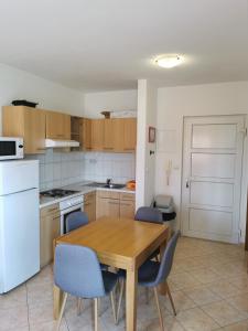 a kitchen with a wooden table and blue chairs at Apartman Katarina in Seget Vranjica