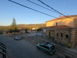 dos autos estacionados en un estacionamiento al lado de un edificio en Apartamentos Sierra y Mar Aldealengua de Pedraza, en Ceguilla