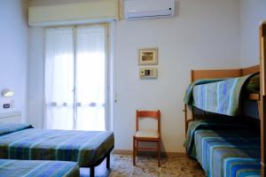 a bedroom with two bunk beds and a chair at Hotel Chiara in Rimini