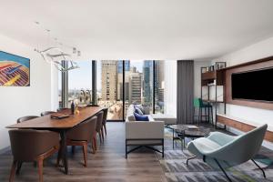 a living room with a table and chairs and a tv at Le Meridien Melbourne in Melbourne