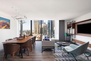 a living room with a table and chairs and a tv at Le Méridien Melbourne in Melbourne