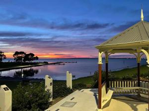 a gazebo with a sunset over the water at Beach view Rippleside Cottage in Geelong West