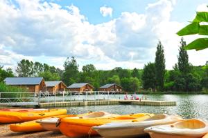 a group of kayaks sitting on the shore of a lake at Résidence Goélia Les Cottages du Lac in Coly