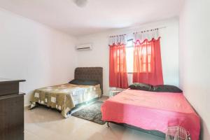 a bedroom with two beds and a window with red curtains at Espaço Ideal de Itaipuaçú in Maricá