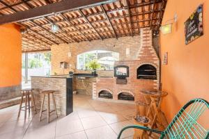 a kitchen with a brick fireplace and a bar with stools at Espaço Ideal de Itaipuaçú in Maricá