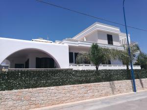 una casa blanca con una pared y una palmera en Hotel Villa Giovanna, en Torre Suda
