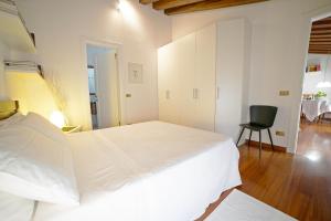 a white bedroom with a large bed and a chair at Apartment Deluxe Isola Di Mezzo in Treviso