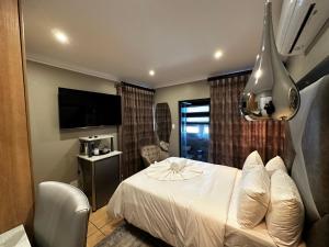 Habitación de hotel con cama y TV en Urban Villas Guest House, en Pretoria