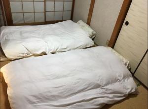 2 Betten in einem Zimmer mit weißer Bettwäsche in der Unterkunft TOMO HOUSE in Taketoyo