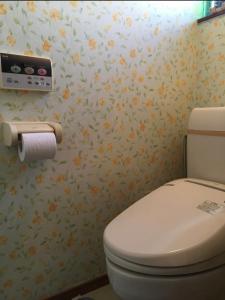 uma casa de banho com WC com flores na parede em TOMO HOUSE em Taketoyo
