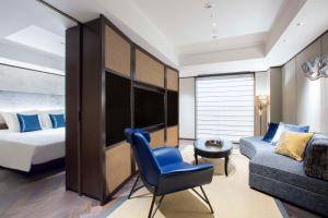 a hotel room with a bed and a blue chair and a couch at Dhawa Yura Kyoto in Kyoto
