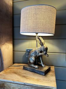 uma estátua de um coelho sobre uma mesa com uma lâmpada em The Cabin Near Stansted Airport em Little Hallingbury