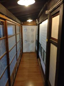 pasillo de una habitación con puerta y suelo de madera en Momiji hostel, en Minami Aso