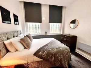 a bedroom with a large bed and two windows at Modern Central 5 Bed Apartment in Liverpool