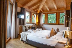 ein Schlafzimmer mit einem großen Bett in einem Zimmer mit Fenstern in der Unterkunft Hotel Ciasa Soleil in Stern