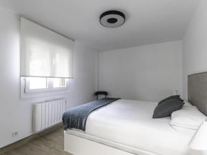 a white bedroom with a bed and a window at Munoa By Kabia Gestion in Barakaldo
