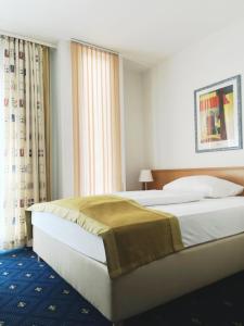 a bedroom with two beds and a large window at Hotel Am Schlosspark , Wiesbaden in Wiesbaden