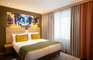 a bedroom with a large bed with yellow pillows at Leonardo Boutique Hotel Salzburg Gablerbräu in Salzburg