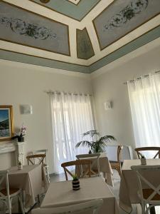 ein Esszimmer mit Tischen, Stühlen und einer Decke in der Unterkunft Palazzo dei Baroni in San Bartolomeo in Galdo
