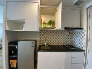 a kitchen with white cabinets and a white refrigerator at The Yudhistira Tower by Asoka in Yogyakarta