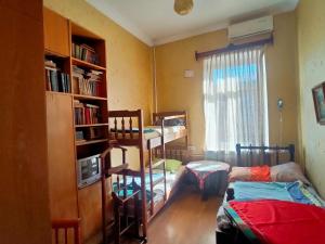 a room with two beds and a book shelf at Guest House Irina Tbilisi in Tbilisi City
