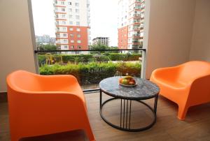 İnanlar City Hotel في يومرا: غرفة بها كرسيين برتقال وطاولة عليها فاكهة