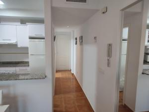 una cocina blanca con armarios blancos y un pasillo en Apartamento Palomares II, en Palomares
