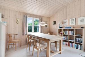 ein Esszimmer mit einem Tisch, Stühlen und einem Bücherregal in der Unterkunft Cozy Cottage In A Quiet Area Close To The Beach in Dannemare