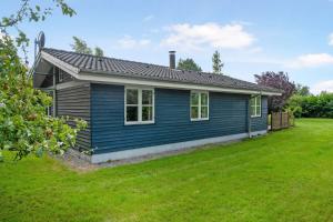 ein blaues Haus mit einem grünen Hof in der Unterkunft Cozy Cottage In A Quiet Area Close To The Beach in Dannemare
