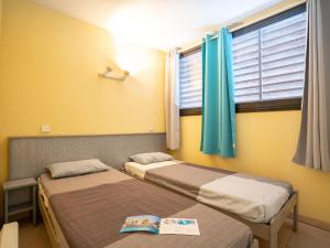 カップ・ダグドにあるApartment Les Rivages de Rochelongue-2 by Interhomeの黄色い壁の客室で、ベッド2台、窓が備わります。