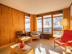 uma sala de estar com um sofá, uma cadeira e uma televisão em Apartment Le Pramecou-3 by Interhome em Tignes