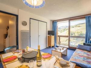 a living room with a table with a bottle of wine at Apartment Pegase Phenix-53 by Interhome in Le Corbier