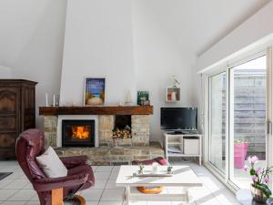 a living room with a fireplace and a chair at Holiday Home Tal Ar Mor - PLC213 by Interhome in Plounévez-Lochrist