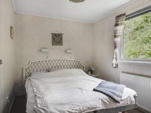 Schlafzimmer mit einem weißen Bett und einem Fenster in der Unterkunft Chalet Västanvik Snickarhagen - OST047 by Interhome in Motala