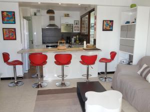salon z kuchnią i czerwonymi barowymi stołkami w obiekcie Apartment Le Paradou by Interhome w mieście Virebelle