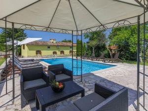 eine Terrasse mit Stühlen und einen Pool mit einem Zelt in der Unterkunft Holiday Home Donada by Interhome in Nedeščina